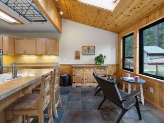 This charming kitchen and dining area features warm wood accents throughout, including vaulted wood-paneled ceilings and wainscoting.