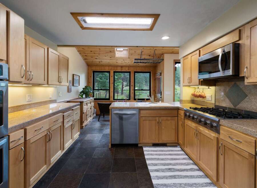 This spacious kitchen boasts beautiful natural wood cabinetry and granite countertops, offering ample storage and workspace.