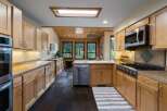 This spacious kitchen boasts beautiful natural wood cabinetry and granite countertops, offering ample storage and workspace.