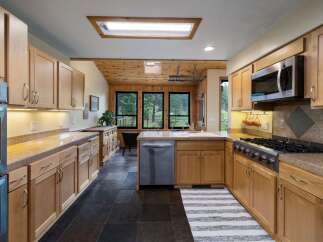 This spacious kitchen boasts beautiful natural wood cabinetry and granite countertops, offering ample storage and workspace.