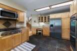 This spacious kitchen features warm wood cabinetry and granite countertops, complemented by stainless steel appliances including a gas range and a double oven.