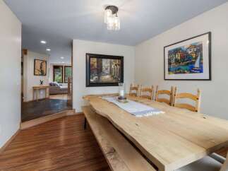 Experience elegant dining in this spacious room featuring a unique live-edge wooden table and comfortable seating.