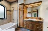 This luxurious bathroom features a spacious bathtub and shower area with elegant tile work and an arched window.