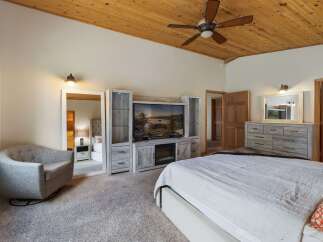 Experience ultimate comfort in this spacious master bedroom, featuring a cozy armchair and a large entertainment center with a fireplace.