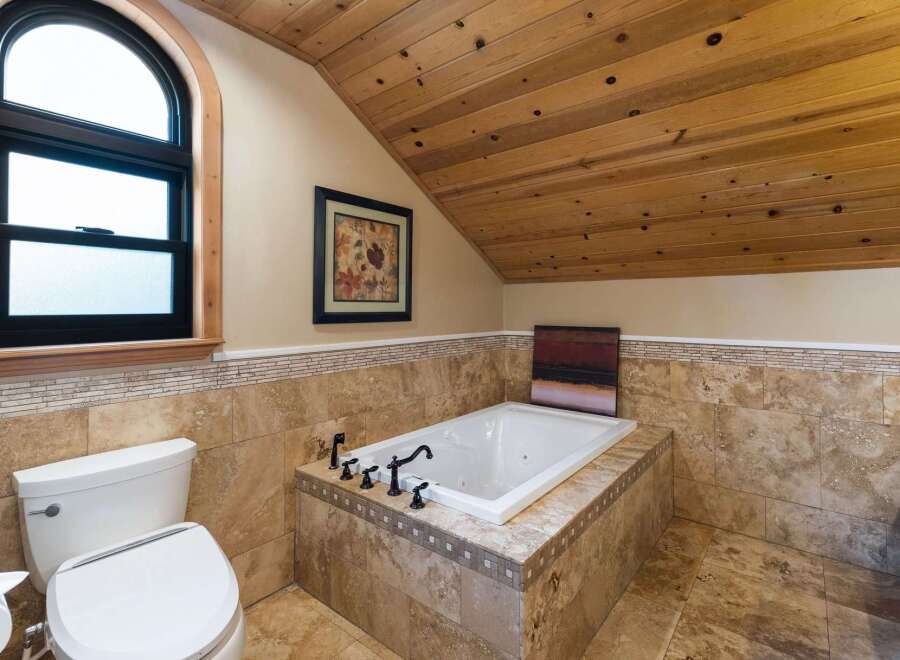 Indulge in relaxation in this luxurious bathroom featuring a deep soaking tub surrounded by elegant travertine tile.