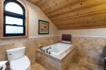 Indulge in relaxation in this luxurious bathroom featuring a deep soaking tub surrounded by elegant travertine tile.