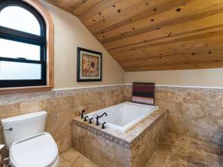 Indulge in relaxation in this luxurious bathroom featuring a deep soaking tub surrounded by elegant travertine tile.