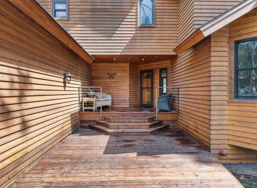 Step onto the expansive wooden deck and be welcomed by the charming entrance of this beautiful home.