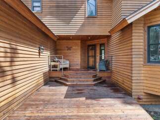Step onto the expansive wooden deck and be welcomed by the charming entrance of this beautiful home.
