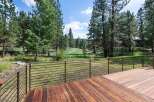 Enjoy the serene natural beauty from this expansive wooden deck, featuring modern metal railings for unobstructed views.