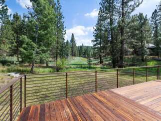 Enjoy the serene natural beauty from this expansive wooden deck, featuring modern metal railings for unobstructed views.