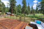 Enjoy the serene mountain lifestyle from this expansive wooden deck, offering breathtaking views of the surrounding pine forest and lush meadow.