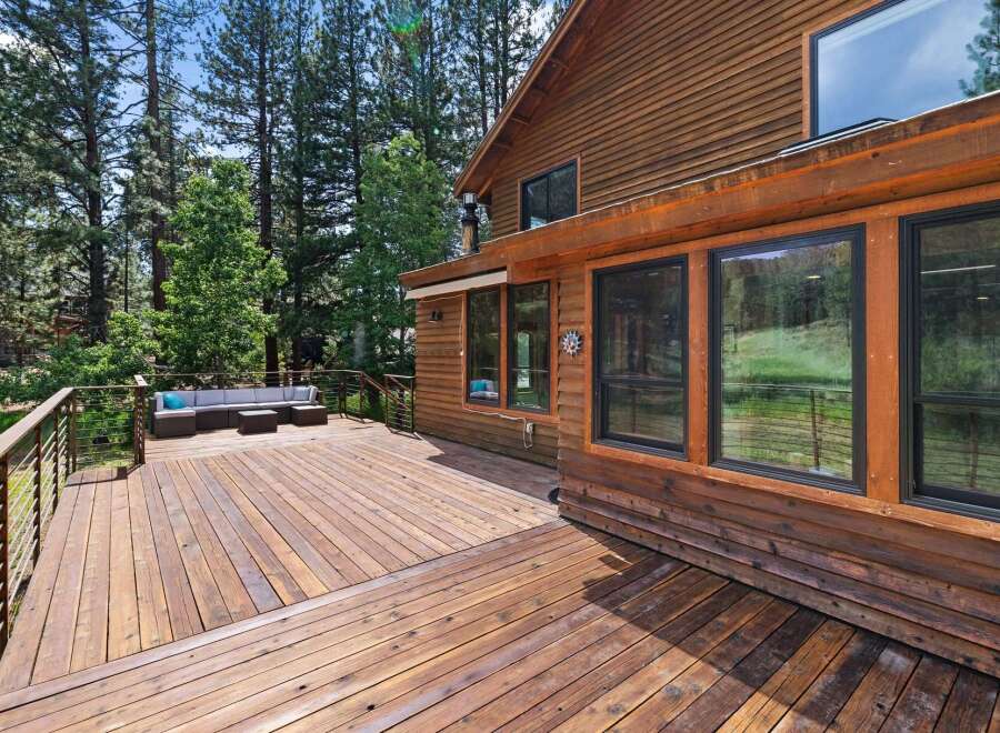 Enjoy the serene mountain lifestyle from this expansive wooden deck, perfect for entertaining or relaxing amidst the tall pine trees.