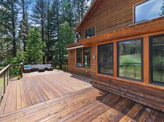 Enjoy the serene mountain lifestyle from this expansive wooden deck, perfect for entertaining or relaxing amidst the tall pine trees.