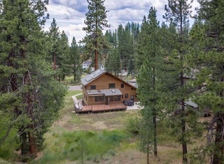 Nestled amidst tall pine trees, this charming wooden home offers a serene retreat.