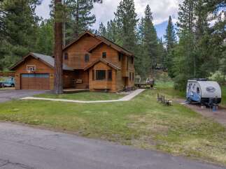 Nestled amidst tall pine trees, this charming wooden home offers a serene retreat.