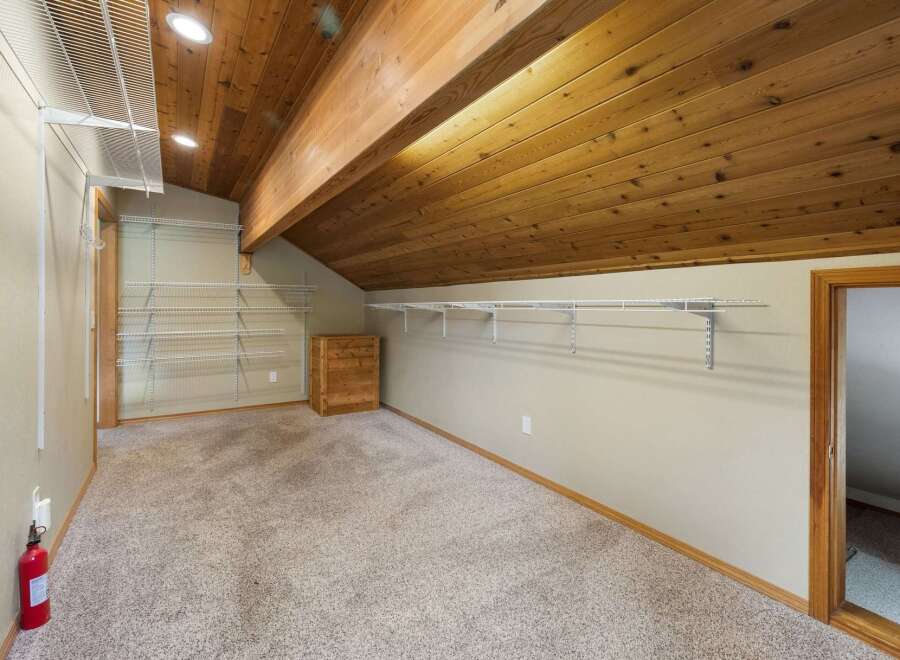 Discover ample storage in this spacious walk-in closet, featuring extensive shelving and a charming wooden dresser.