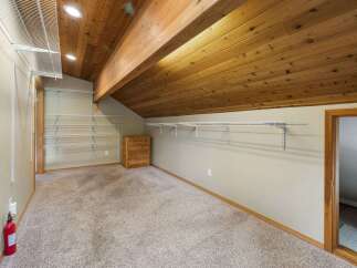 Discover ample storage in this spacious walk-in closet, featuring extensive shelving and a charming wooden dresser.