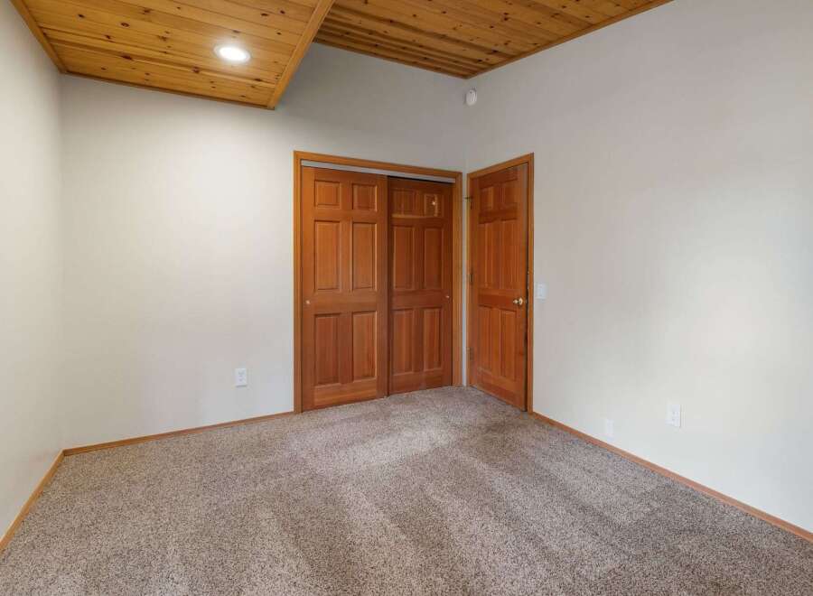 Step into this inviting room featuring a warm wooden ceiling and plush carpeting for ultimate comfort.