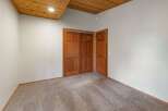 Step into this inviting room featuring a warm wooden ceiling and plush carpeting for ultimate comfort.