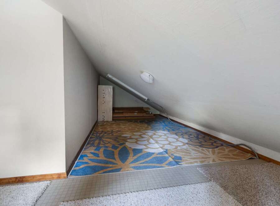 Discover versatile living space in this attic room, perfect for a home office or extra storage.