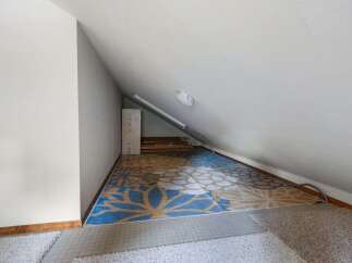 Discover versatile living space in this attic room, perfect for a home office or extra storage.
