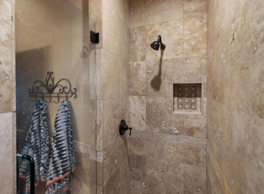 Experience luxury in this stunning shower featuring elegant travertine tile work and a convenient built-in niche for toiletries.