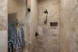 Experience luxury in this stunning shower featuring elegant travertine tile work and a convenient built-in niche for toiletries.