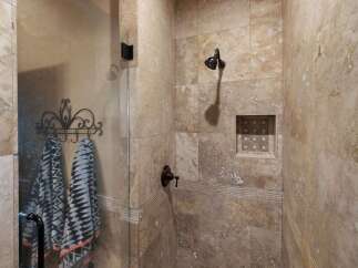 Experience luxury in this stunning shower featuring elegant travertine tile work and a convenient built-in niche for toiletries.