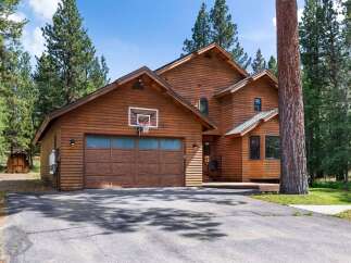 Experience mountain living in this stunning wood-sided home, perfectly nestled among tall pine trees.