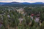 Nestled amidst a dense forest, this aerial view showcases a charming neighborhood with homes scattered among tall pine trees.