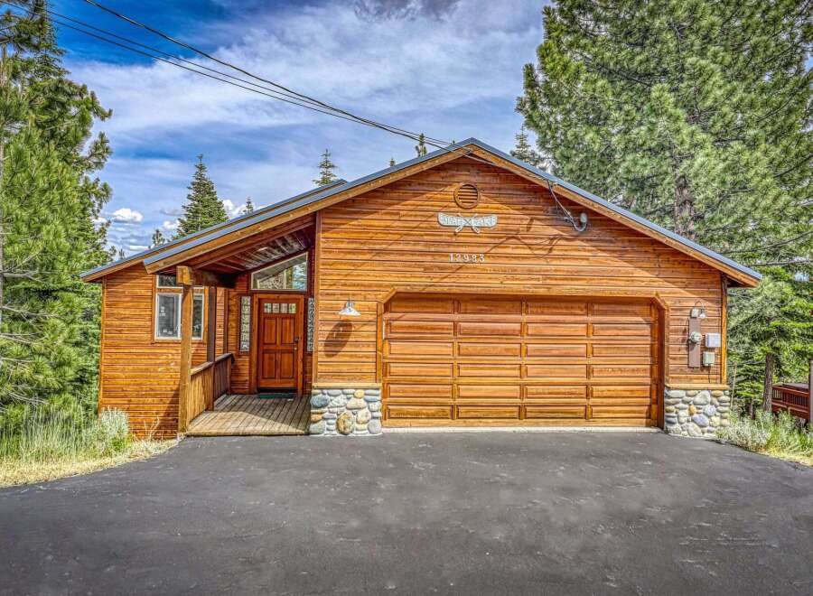 Experience rustic charm in this beautiful wooden cabin, featuring a spacious garage and a welcoming front porch.