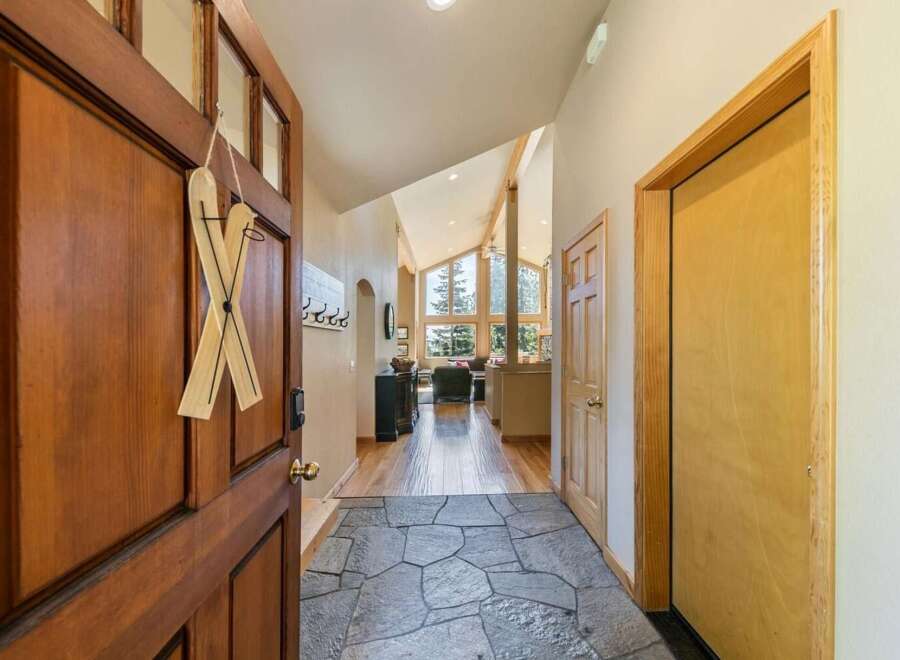 Step into this welcoming entryway featuring a rustic wooden door adorned with charming ski decor.