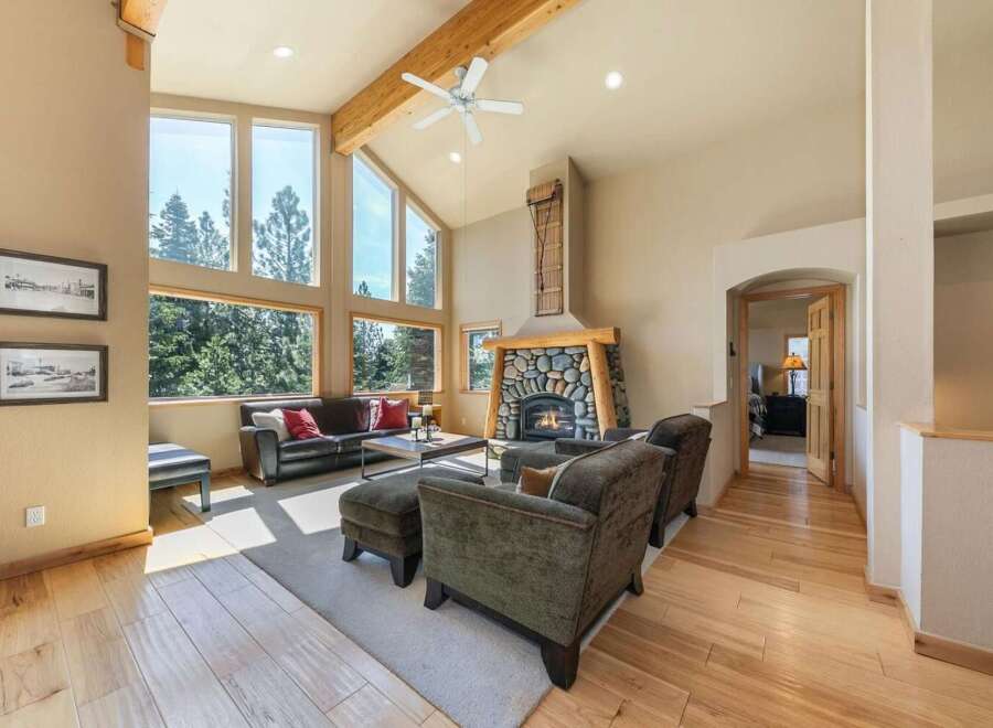 Experience rustic charm and modern comfort in this stunning living room, featuring a grand stone fireplace and soaring vaulted ceilings with exposed wooden beams.