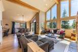 Experience breathtaking mountain views from this stunning living room, featuring a soaring vaulted ceiling with exposed wooden beams and expansive windows that flood the space with natural light.