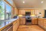 Experience the charm of this rustic kitchen, featuring warm knotty pine cabinetry and a spacious double sink overlooking a picturesque landscape.