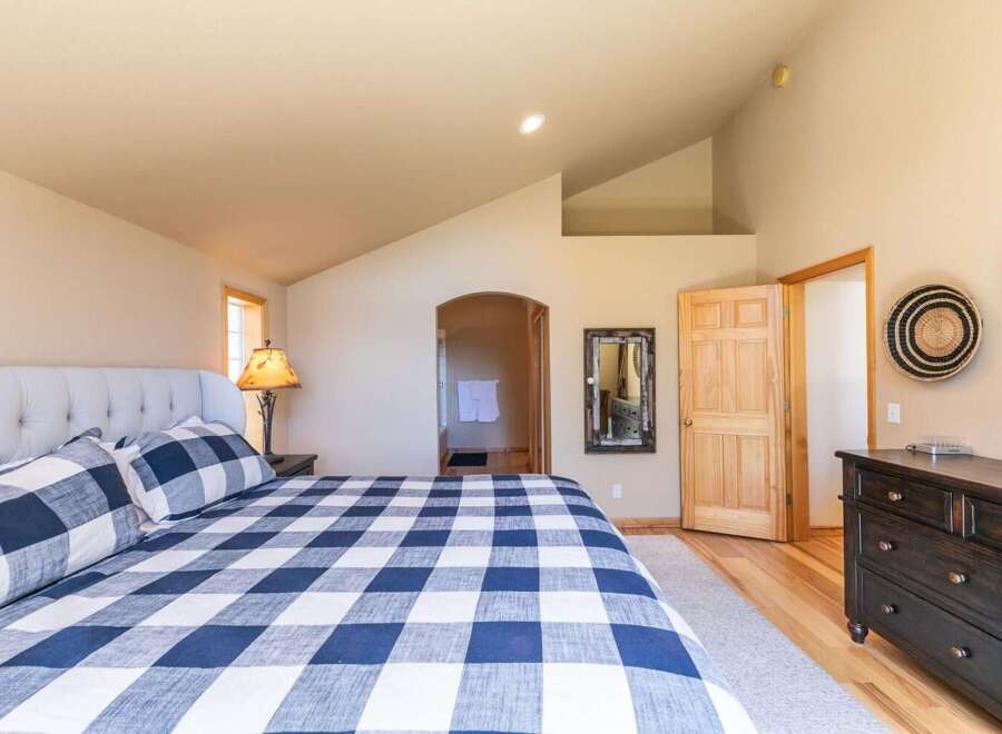 Experience comfort and style in this inviting bedroom, featuring a plush tufted headboard and a striking blue and white buffalo check duvet.