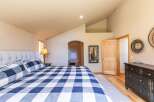 Experience comfort and style in this inviting bedroom, featuring a plush tufted headboard and a striking blue and white buffalo check duvet.