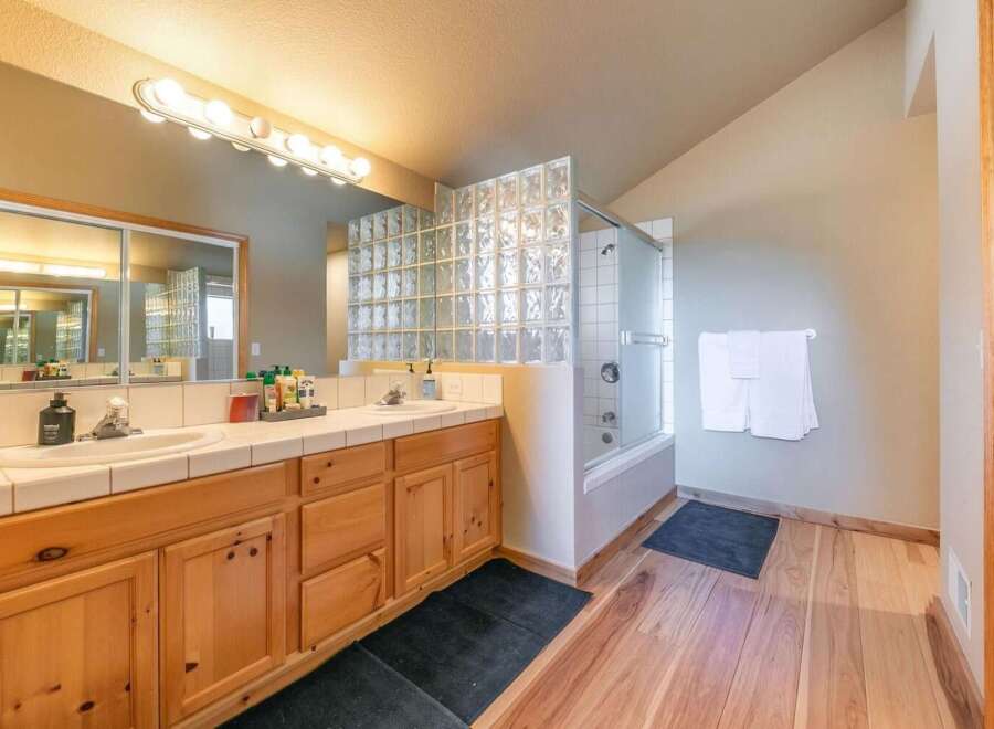 This spacious bathroom features a double vanity with ample counter space and wooden cabinetry, perfect for storage.