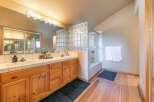 This spacious bathroom features a double vanity with ample counter space and wooden cabinetry, perfect for storage.