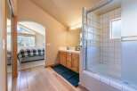 This charming bathroom features a wooden vanity with a tiled countertop and a glass-enclosed shower-tub combo with unique glass block accents.