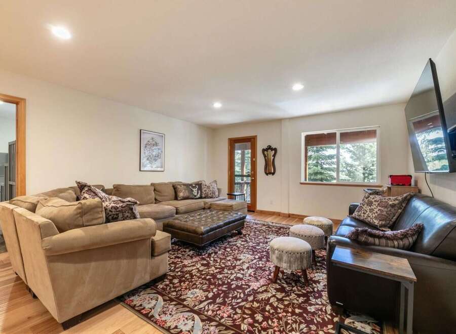 Step into this inviting living room, featuring a spacious sectional sofa perfect for gatherings and a large, ornate rug that adds a touch of elegance.