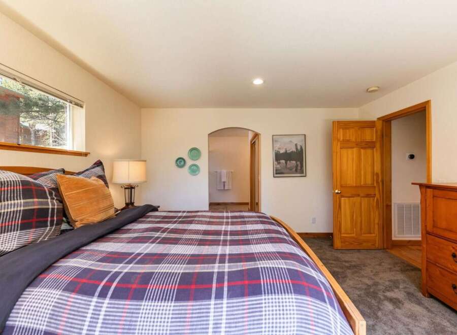Experience cozy comfort in this inviting bedroom, featuring a plush plaid comforter and a warm wooden bed frame.