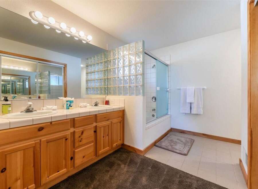 This spacious bathroom features a double vanity with ample counter space and wooden cabinetry, perfect for storage.