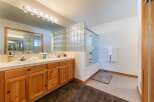 This spacious bathroom features a double vanity with ample counter space and wooden cabinetry, perfect for storage.
