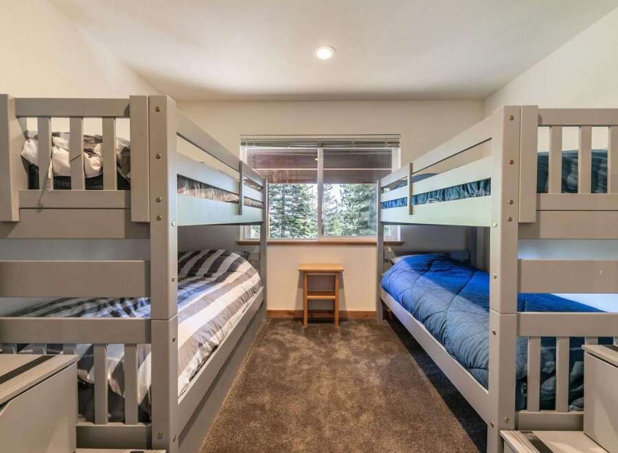 This charming bedroom features two sets of sturdy grey bunk beds, perfect for accommodating family and friends.