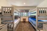 This charming bedroom features two sets of sturdy grey bunk beds, perfect for accommodating family and friends.