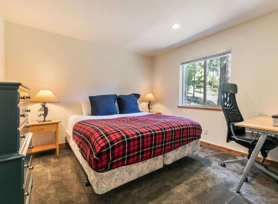 This cozy bedroom features a comfortable queen-size bed adorned with a classic red and black plaid comforter, perfect for a restful night's sleep.