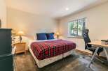 This cozy bedroom features a comfortable queen-size bed adorned with a classic red and black plaid comforter, perfect for a restful night's sleep.