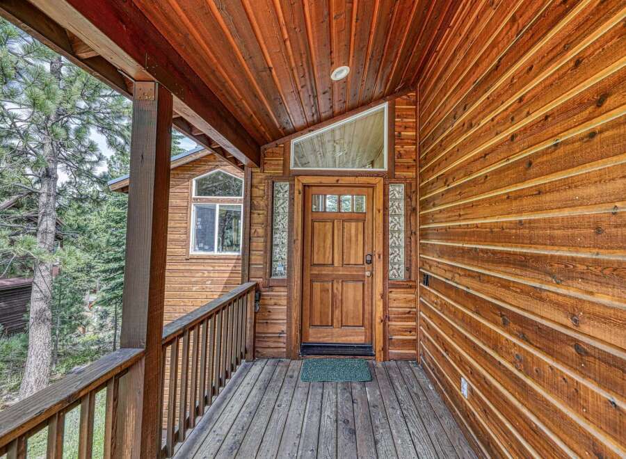 Step onto the inviting wooden porch of this charming cabin, featuring a beautiful natural wood exterior and a welcoming front door.